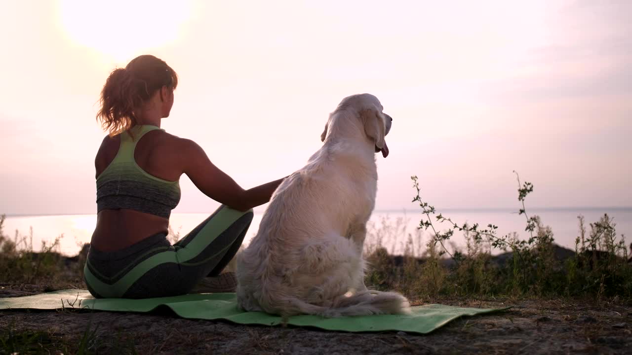 Young woman meditating with her dog aside near sea