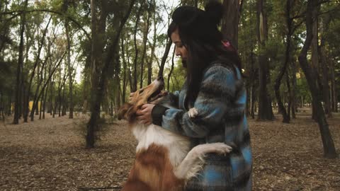 A woman pets her dog in the park