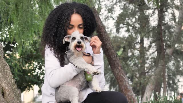 Young woman in a park carrying her schnauzer dog