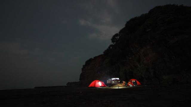 People Camping On A Beautiful Shoreline Beside A Mountain