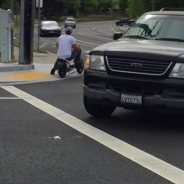 Man in white riding kid motorcycle on street