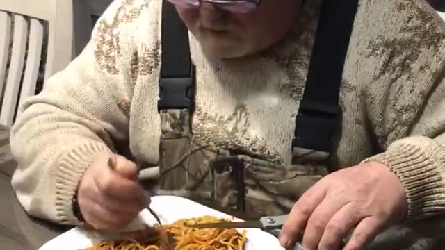 Man uses scissors to make eating spaghetti easier