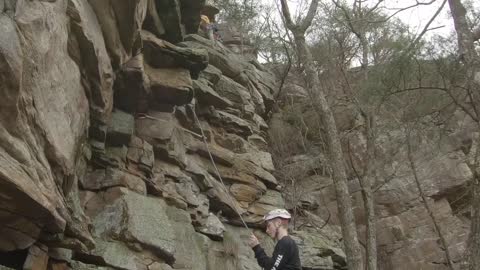 Climber, wearing a helmet, gets hit on the head with a rock.