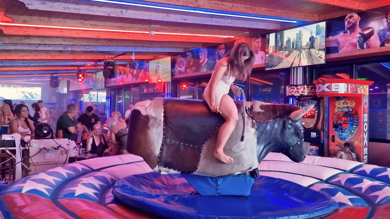 Pretty Girl in Beautiful Dress Riding on a Bull in Benidorm