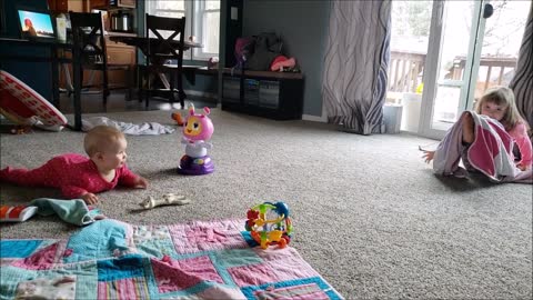 Happy baby laughs at silly big sister