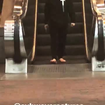 Lady black jacket with hammer and sandals walking backwards escalator