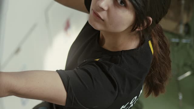 Woman Looking at Up While Hanging on the Climbing Wall