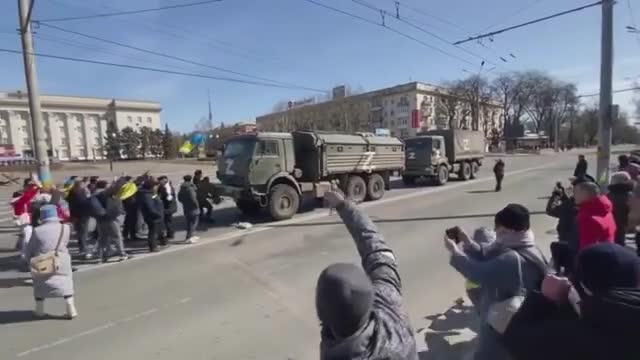 Russian military vehicles leaving Ukraine as Ukrainian protesters confront them on the street.