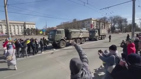 Russian military vehicles leaving Ukraine as Ukrainian protesters confront them on the street.