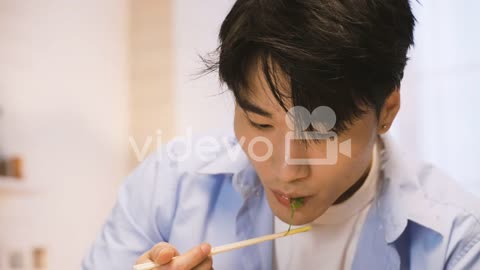 Close Up View Of Japanese Man's Hands Holding Chopsticks Picking Wakame Seaweed In The Kitchen