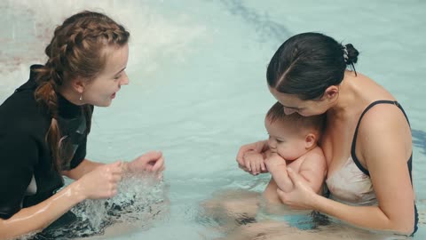 two people playing with a baby in the pool