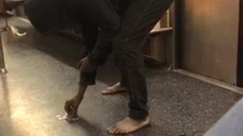 Barefoot woman counts change on subway floor