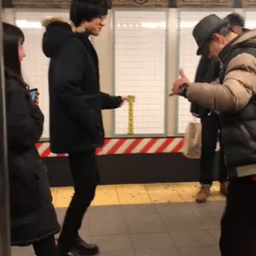 Two men dancing salsa on subway platform