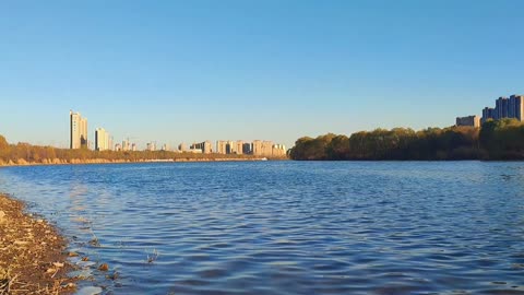 A bend of water under the blue sky surrounds a city