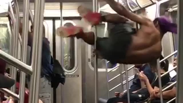 Shirt guy black shorts purple bandana dancing on pole subway