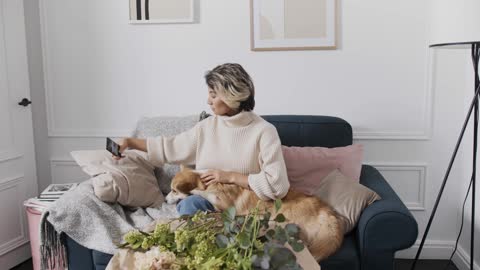 Woman Using Cellphone while Playing the Dog