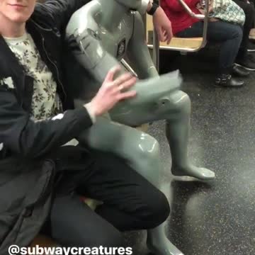 Silver mannequin with sunglasses rides the subway