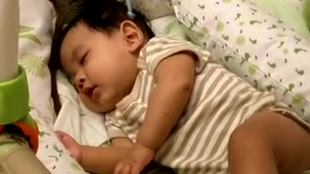 Adorable baby laughing alone while sleeping