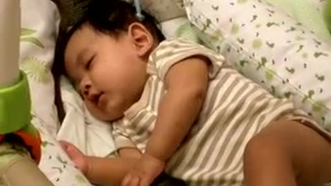 Adorable baby laughing alone while sleeping