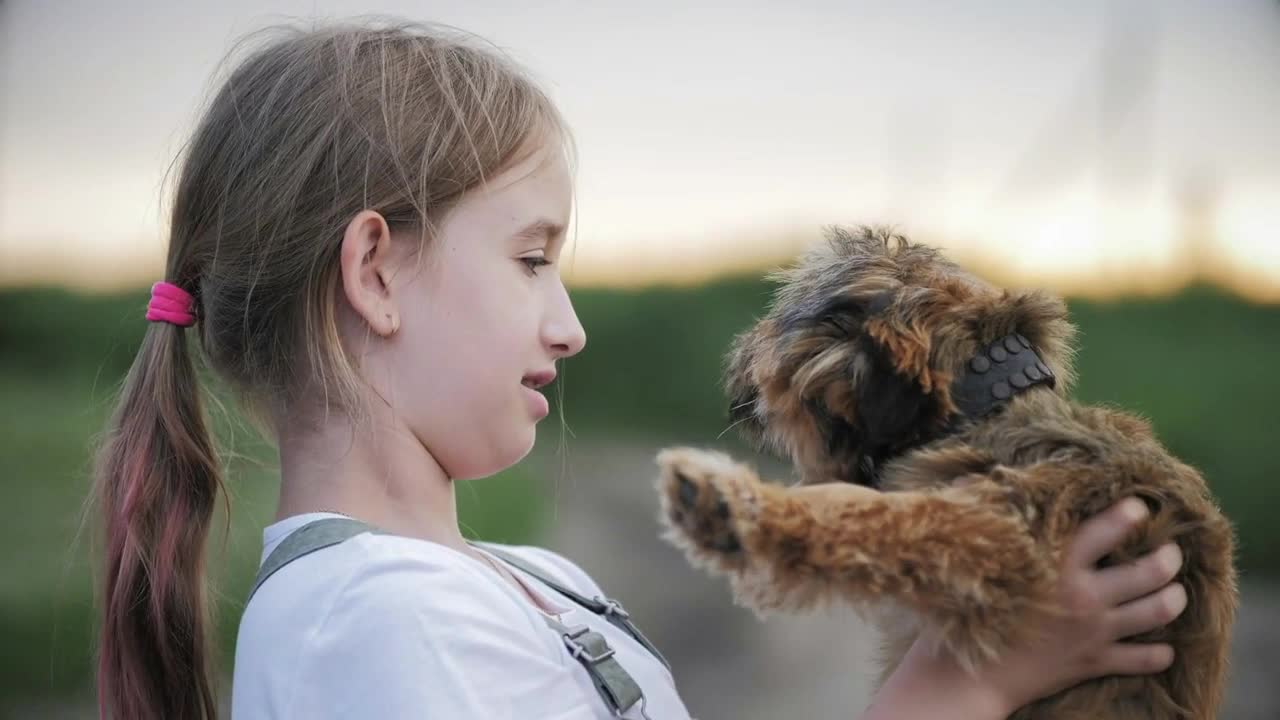 Happy girl play with little puppy. Small dog in arms girl child