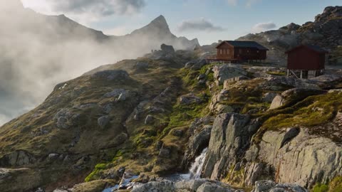 scenic summer shot of clouds passing by a mountain hut on the lofoten islands norway