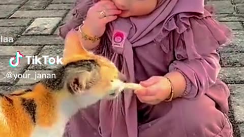 Baby girl eating with cat