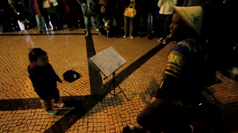 Baby walks up to street performer, steals the show!