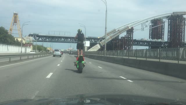 Man Rides Motorcycle Standing Up in Traffic