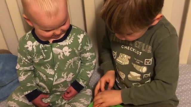 Big brother reads to little brother in his crib