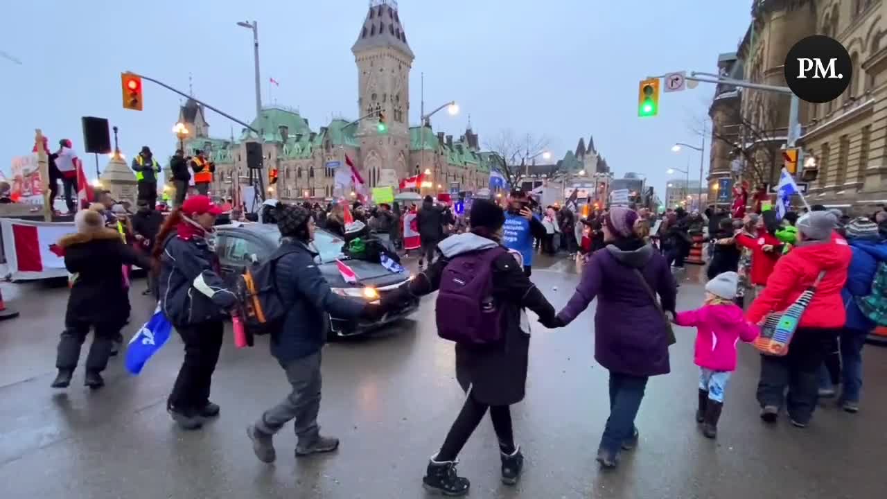 Supporters of the Freedom Convoy hold hands and sing