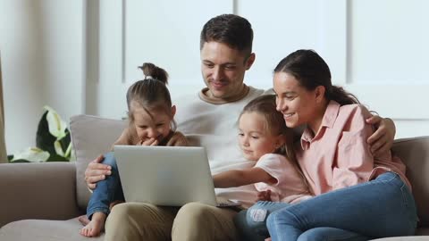 happy family couple watching funny movie cartoons with children Using Personal Computer Laptop