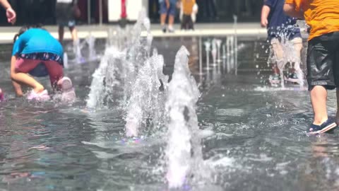 children playing in the fountain in hot summer