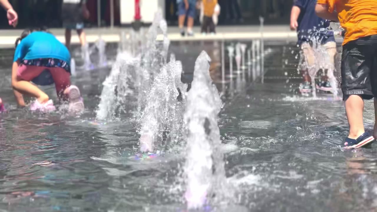 children playing in the fountain in hot summer