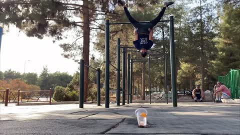 Guy Lands Ball in Cup Using His Mouth Holding Onto Bar Upside Down