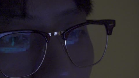 A man wearing glasses who watches TV.