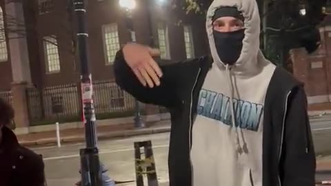 Students confront a masked guy ripping down hostage posters at Harvard Square.