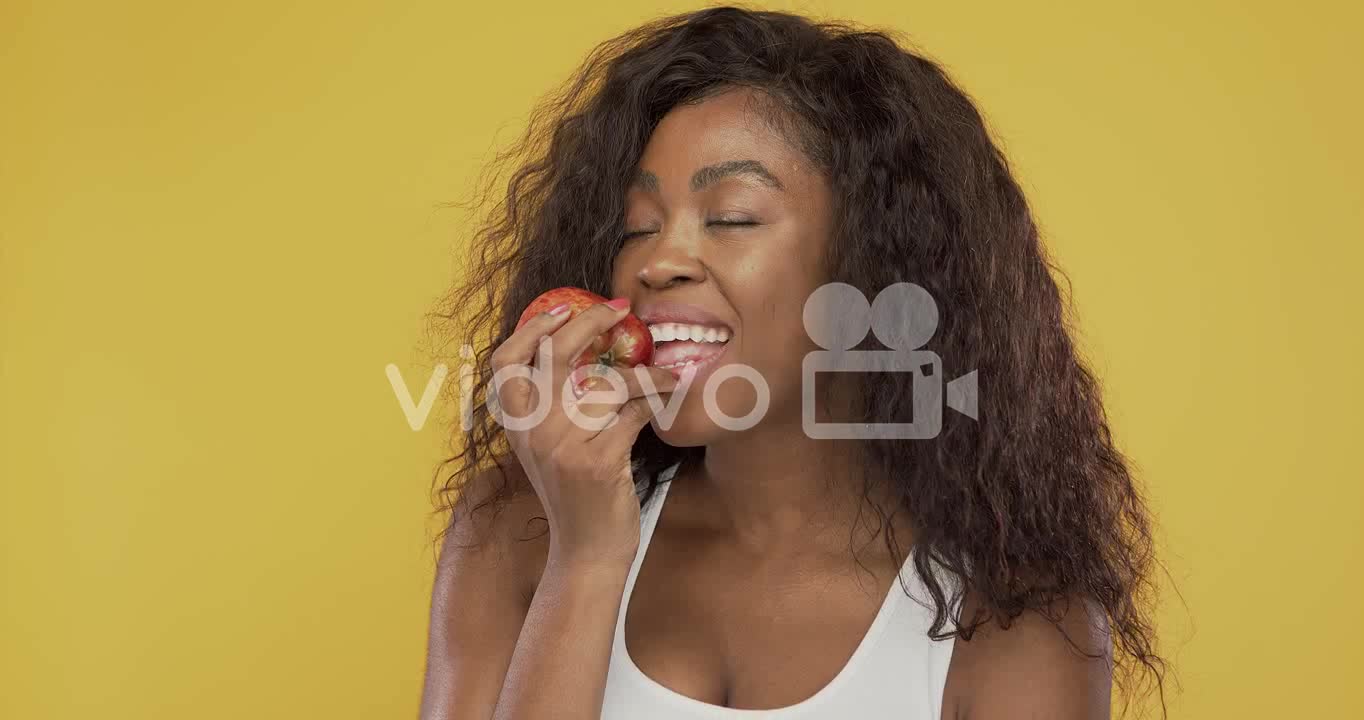 Black woman eating fresh apple-African American female with closed eyes biting ripe juicy apple whil