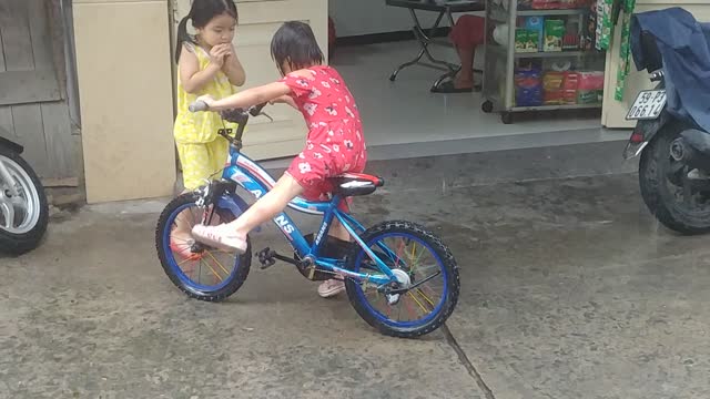 Girl riding a bike and taking a rain shower.