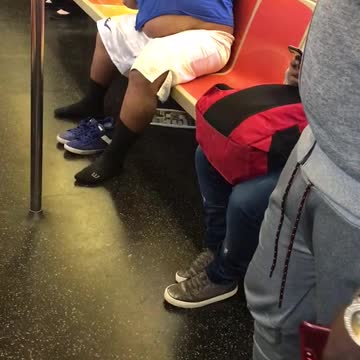 Guy backpack white shorts blue shirt stretching left and right subway orange seats