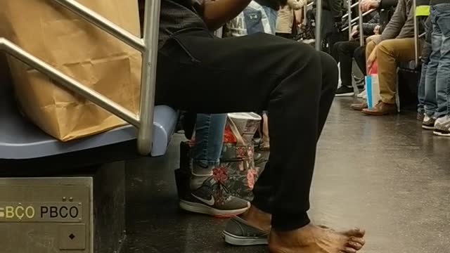 Shoeless man purells hands and feet on subway