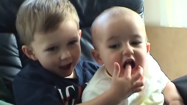 Baby sucking his brother's finger