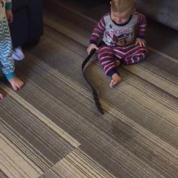 Young Girl Pretends To Walk Baby Using A Belt On His Waist As A Leash