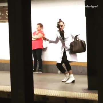 Guy white long coat dancing subway platform headphones
