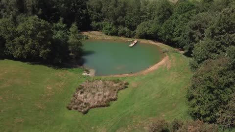 Drone Shot Flying Through Brick Arch to Reveal a Scenic Lake On Edge of Woodland