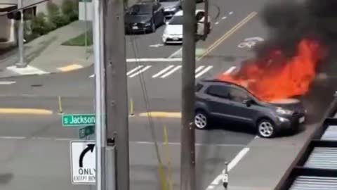 THE CURRENT STATE OF SEATTLE: Car in flames while man exposes himself peeing on the sidewalk.