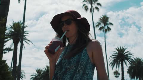 A woman walking and drinking a smoothie