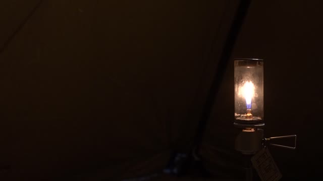 A lamp shining brightly in a dark tent