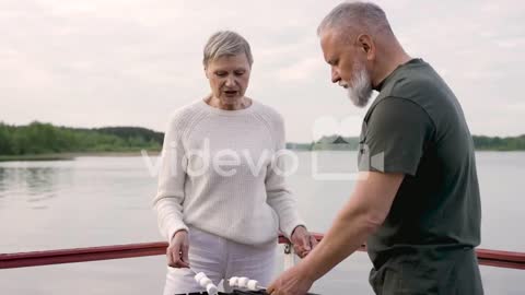 A Couple Of Senior People Roasting Marshmallows Over A Barbecue 1