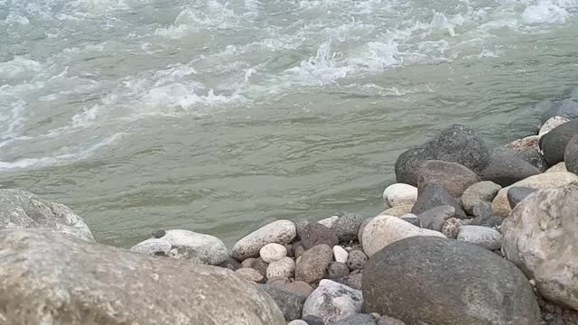 the view of the rocks on the side of the river with rushing water