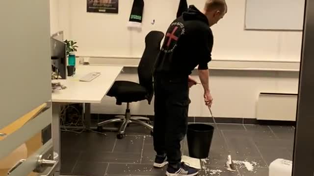 The man sweeps the floor very hard